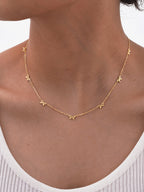 Minimalist gold bow charm necklace on model, delicate 18k gold plated dainty chain jewelry, everyday waterproof necklace close-up