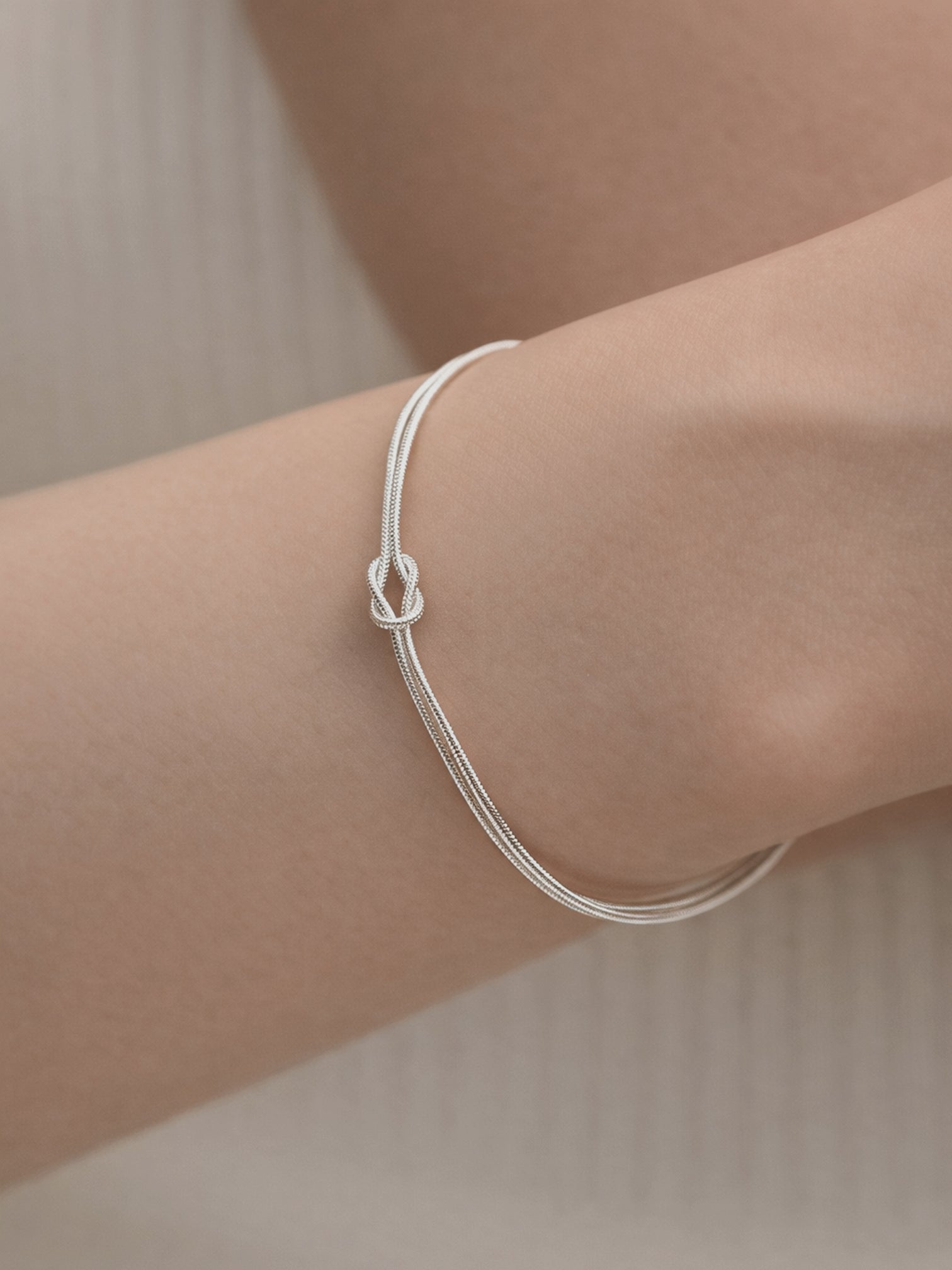 Tate white gold plated minimalist knot bracelet worn on wrist, adjustable chain jewelry by myEdzy