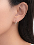 Hailey silver huggie hoop earrings worn by a model | myEdzy