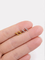Zane gold and white gold triple ball stud earrings size comparison on fingertip | myEdzy