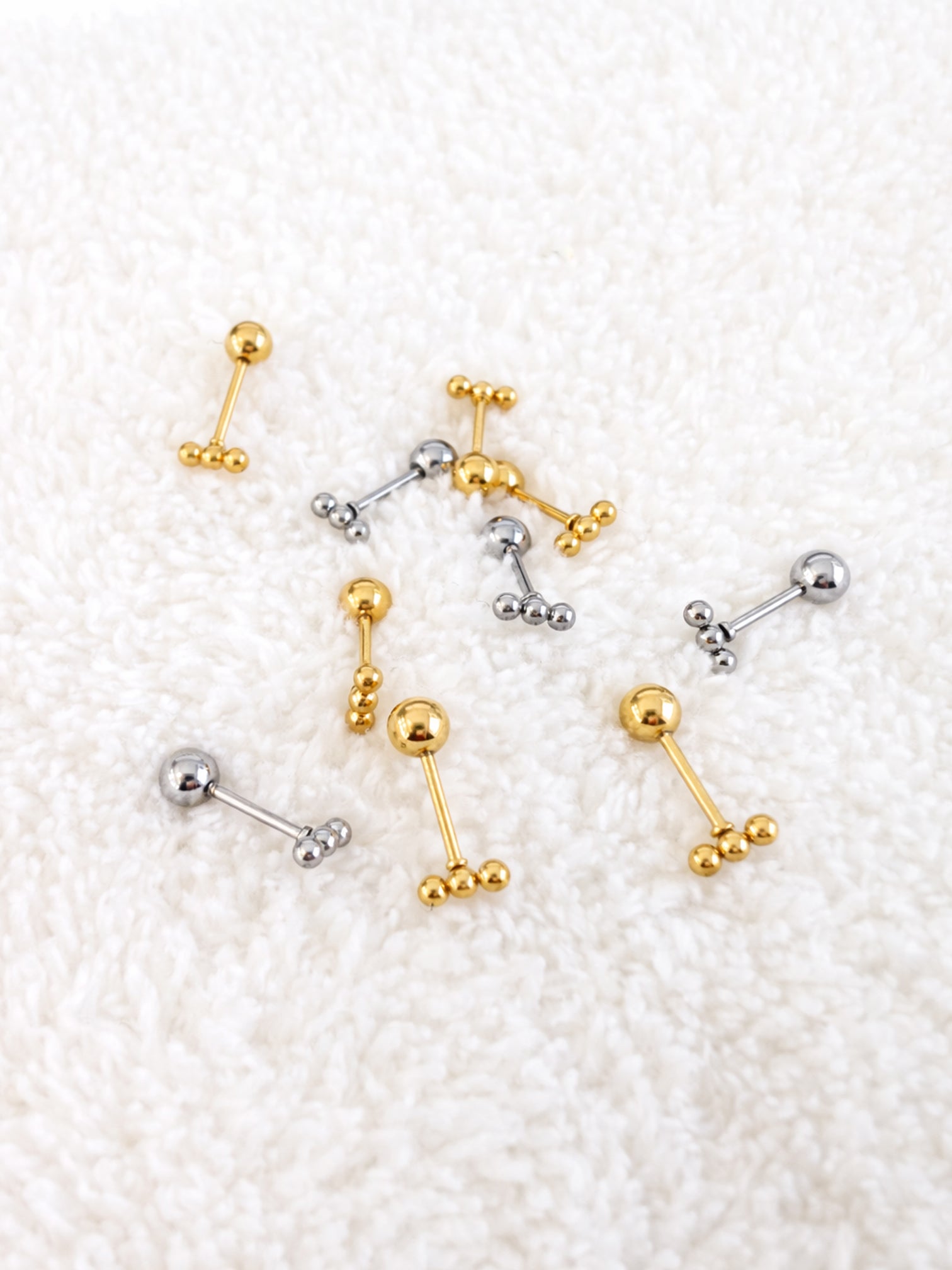 Zane screwback earrings gold and white gold laid on soft texture background minimal jewelry | myEdzy