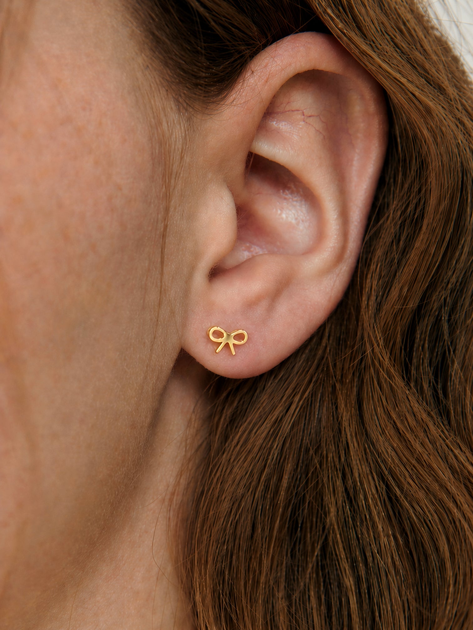 18k gold plated bow stud screwback earrings tiny dainty minimalist hypoallergenic waterproof tarnish resistant everyday jewelry myEdzy close up ear