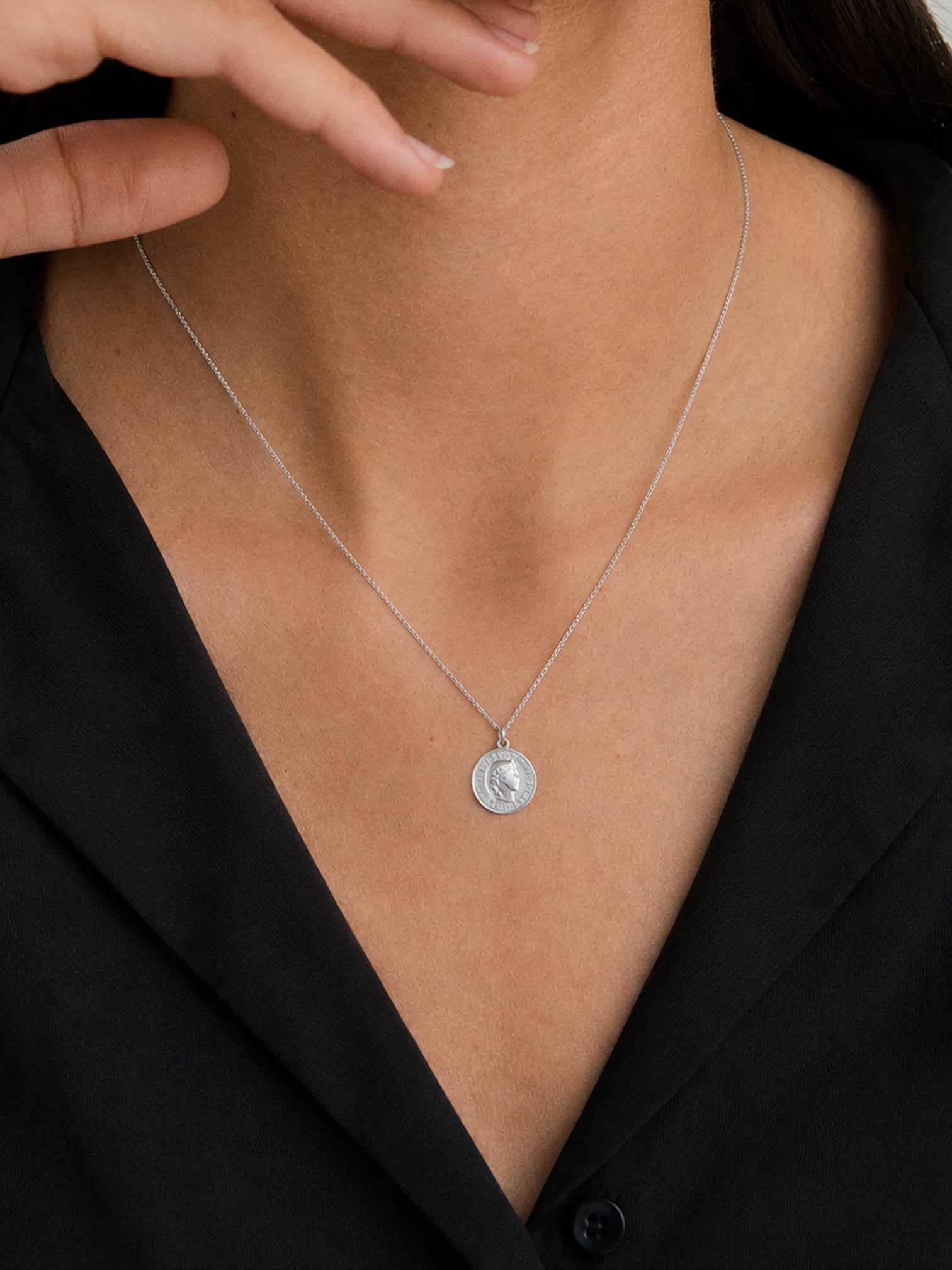 Model wearing myEdzy vintage coin pendant necklace in silver titanium steel, minimalist waterproof tarnish-resistant jewelry for women