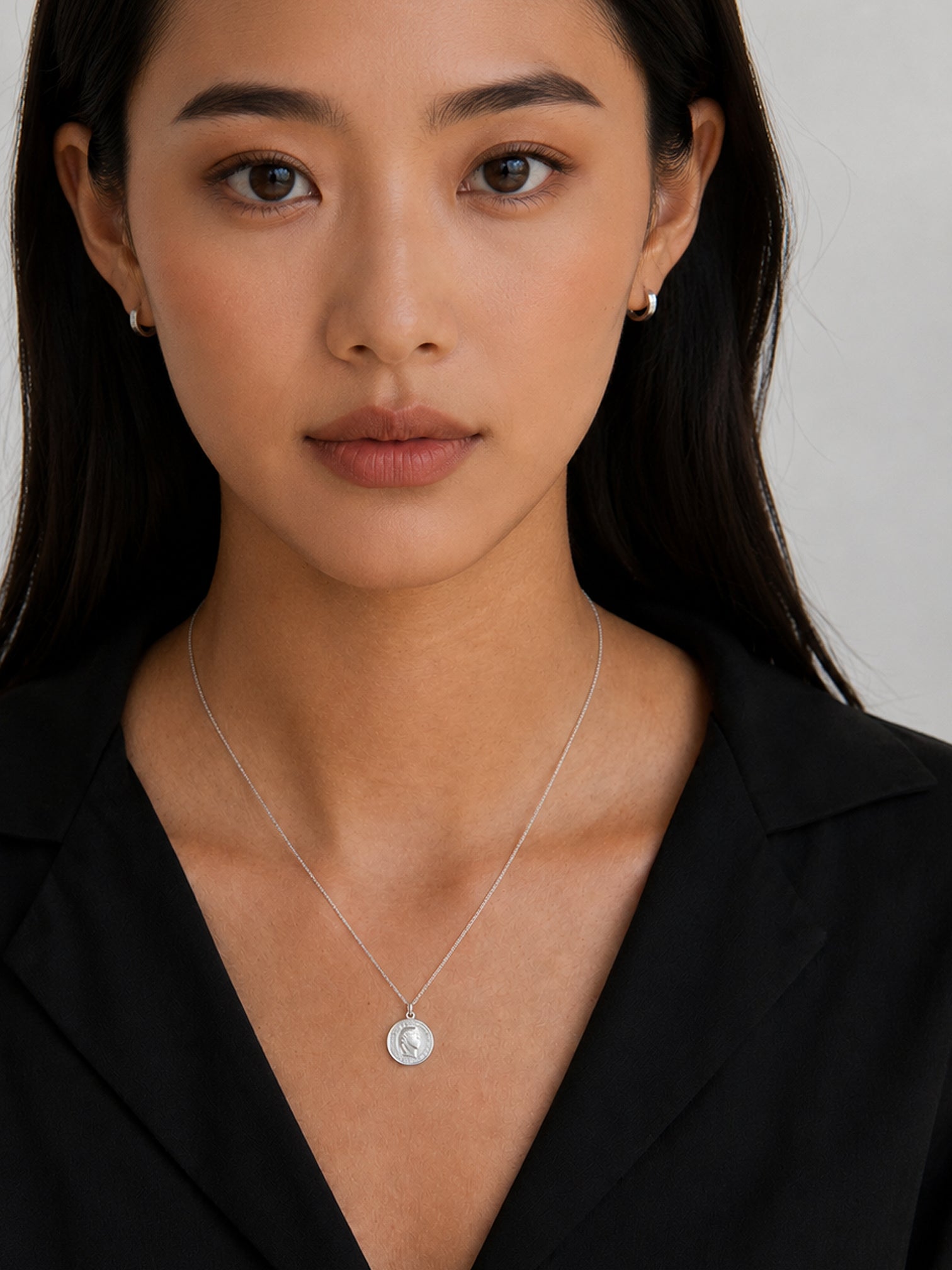 Model wearing myEdzy vintage coin pendant necklace in silver titanium steel, minimalist waterproof jewelry with black outfit