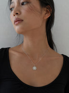 Model wearing myEdzy vintage coin pendant necklace in silver titanium steel, minimalist waterproof jewelry with black casual top