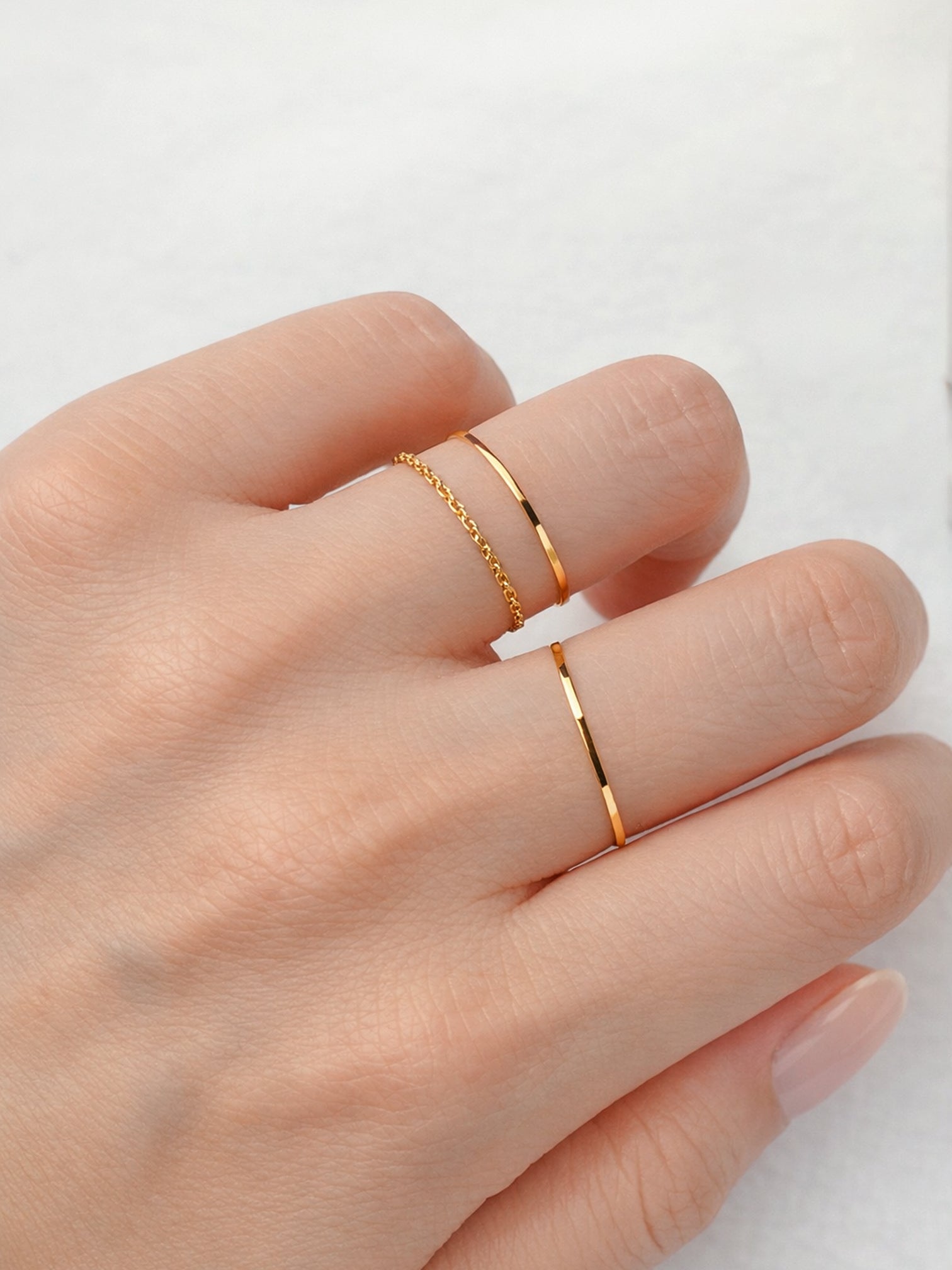 Slim gold stacking ring worn on finger simple dainty band