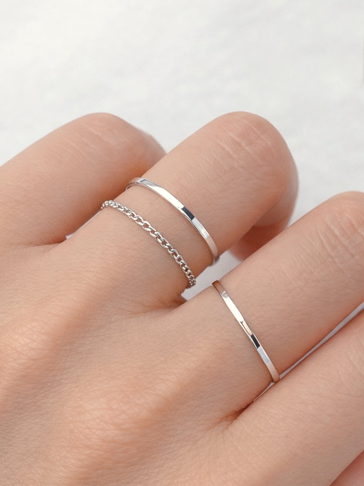 Slim white gold silver stacking ring worn on finger simple dainty band
