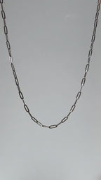 Short looping video of a silver paperclip chain necklace gently moving and reflecting light, with the name “Eden” appearing on screen.