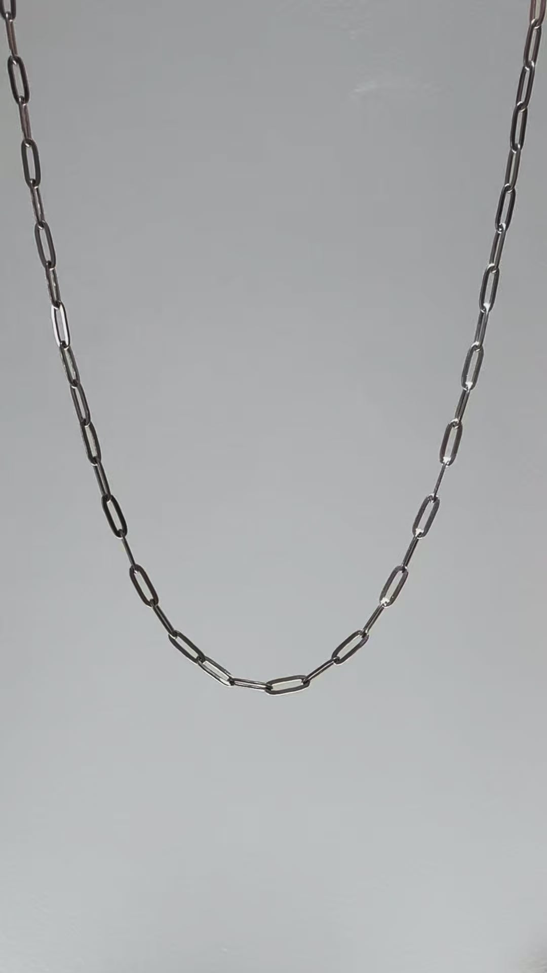 Short looping video of a silver paperclip chain necklace gently moving and reflecting light, with the name “Eden” appearing on screen.