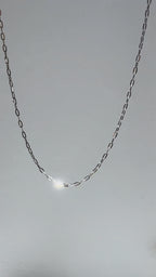 Short looping video of a silver paperclip chain necklace gently moving and reflecting light, with the name “Eden” appearing on screen.