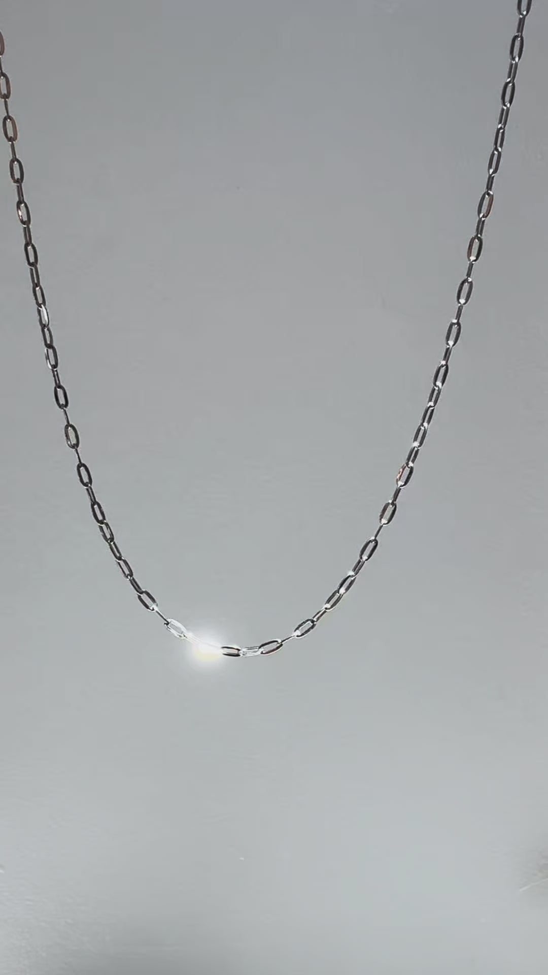 Short looping video of a silver paperclip chain necklace gently moving and reflecting light, with the name “Eden” appearing on screen.