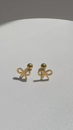 Minimal bow-shaped Bree stud earrings rotating on a turntable, crafted with 18K gold plating over titanium steel, showcasing a delicate open bow design with a polished, lightweight finish on a clean white surface. | myEdzy
